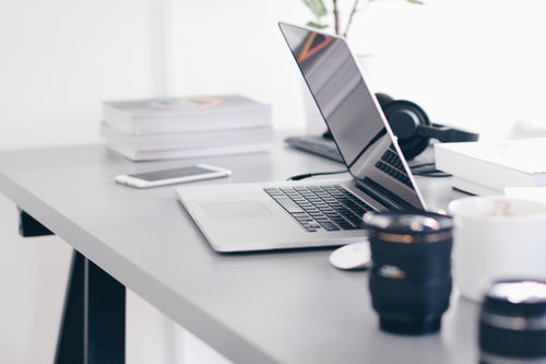 Desk with mug, laptop, mobile and books 