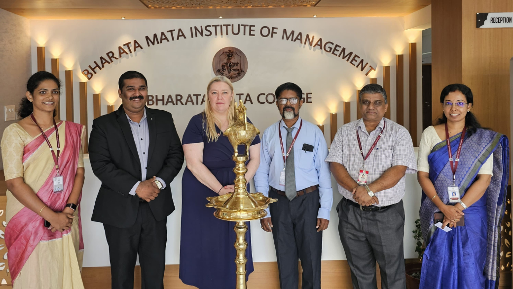 A group of six people posing at the Bharata Mata Institute of Management in India.