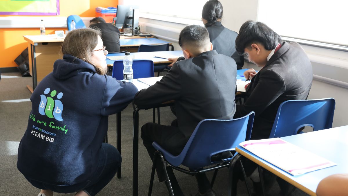 A woman talks to school children sat at a table