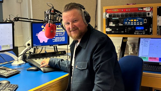 Man sitting in front of  a microphone in a radio studio