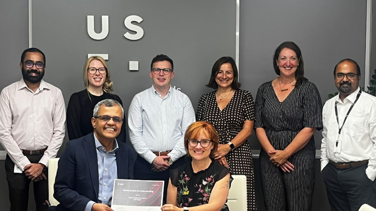 eight people from two businesses (UST and Leeds Trinity University) meet to sign employer agreement.