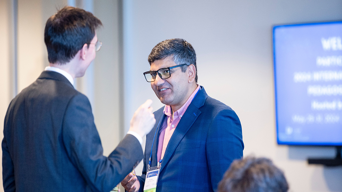 An academic speaking to another academic at an event.