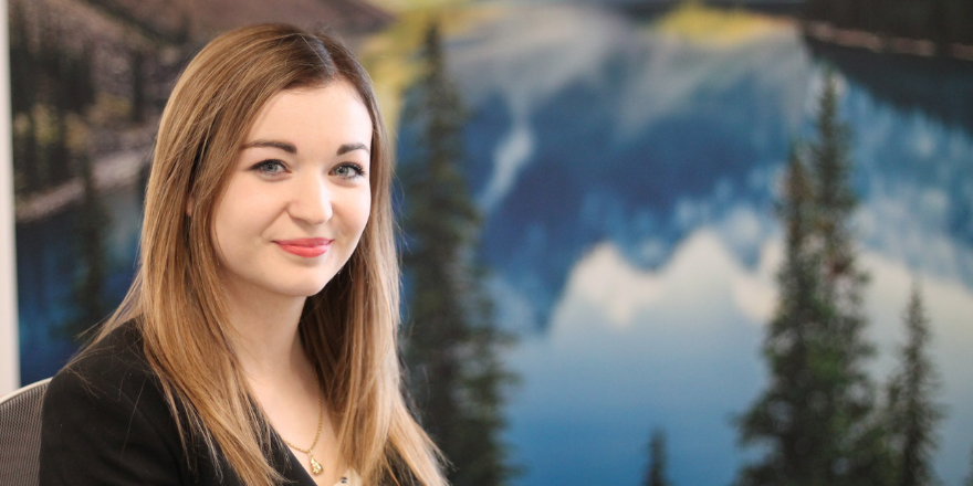 Graduate sat in front of background screen