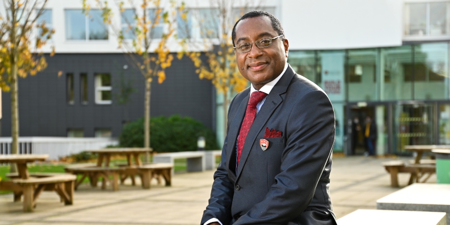 Charles Egbu sitting outside with trees and benches